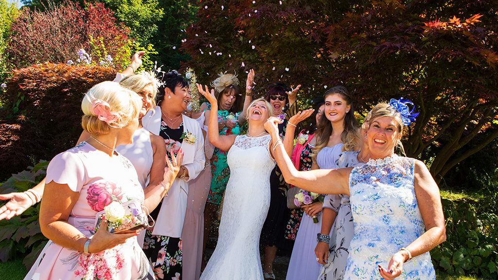 Bride with friends throwing confetti at Carlisle Park, Morpeth