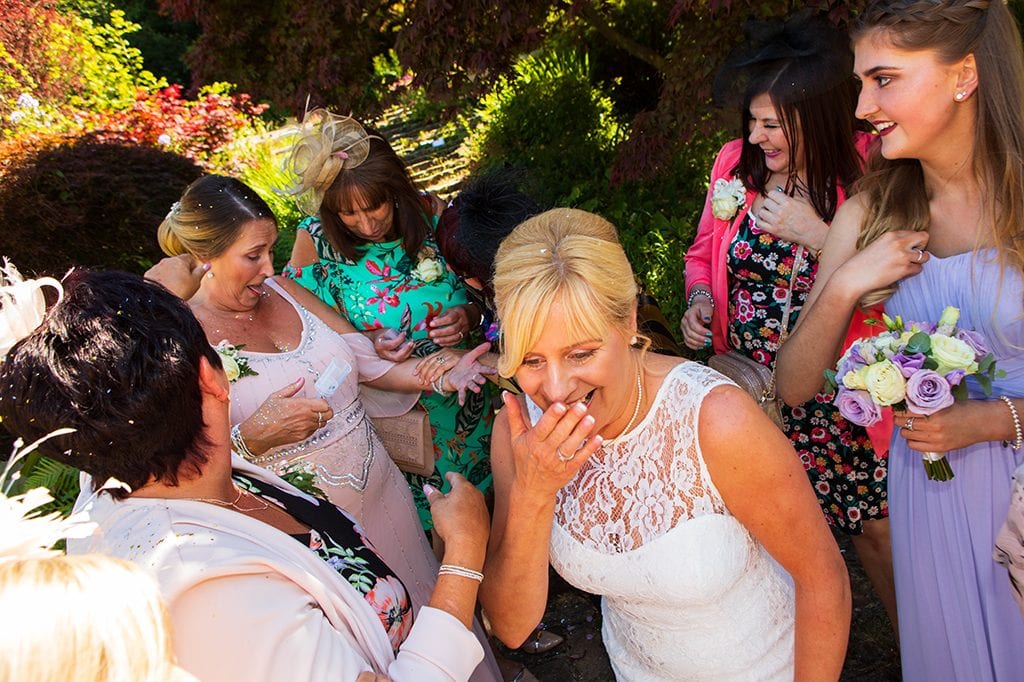 Bride with friends laughing confetti at Carlisle Park, Morpeth