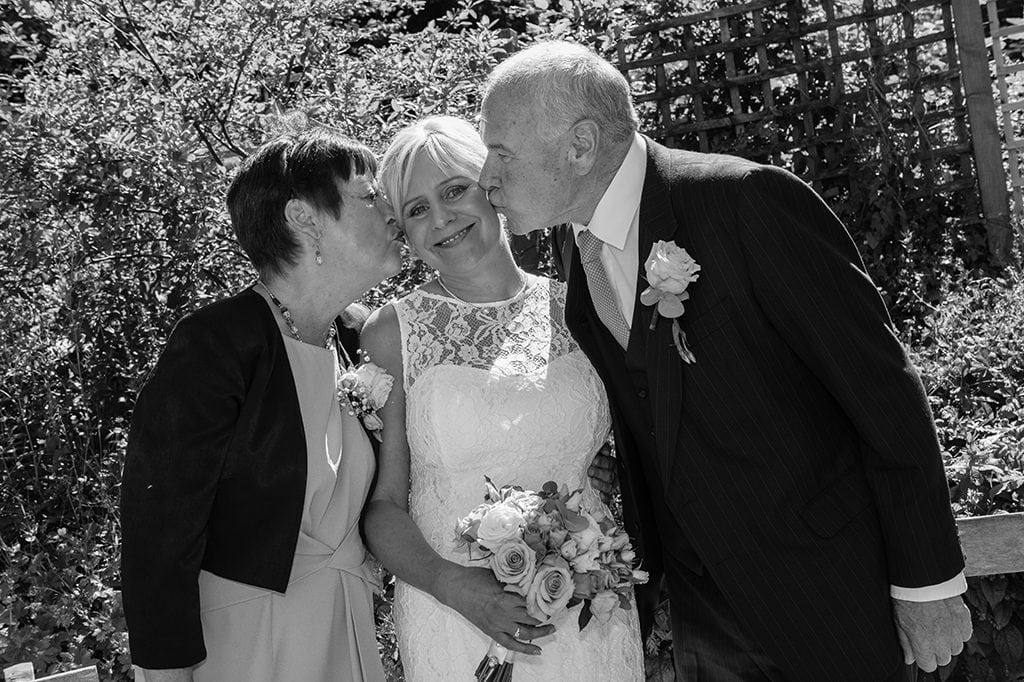 Parents kissing bride at Carlisle Park, Morpeth