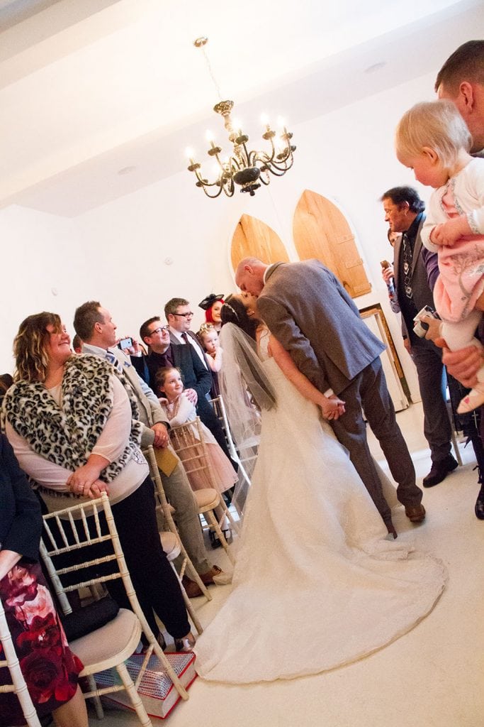 Bride & Groom kissing in the aisle in the white room at Brinkburn Priory, Northumberland