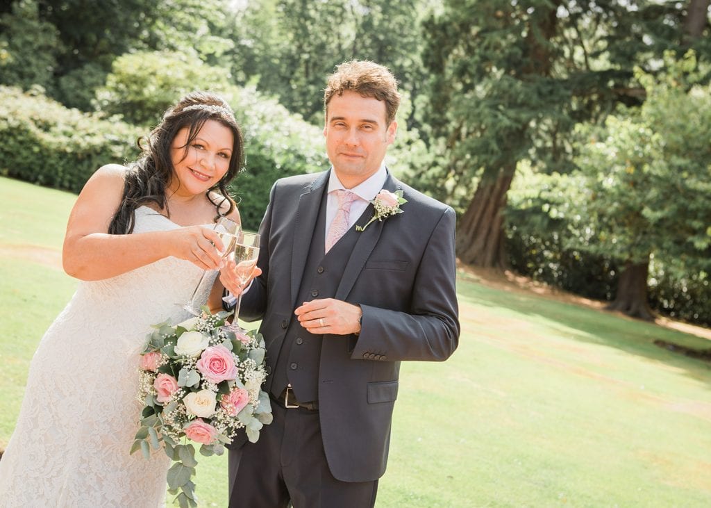 Bride & Groom with champagne in the grounds of Linden Hall in Northumberland