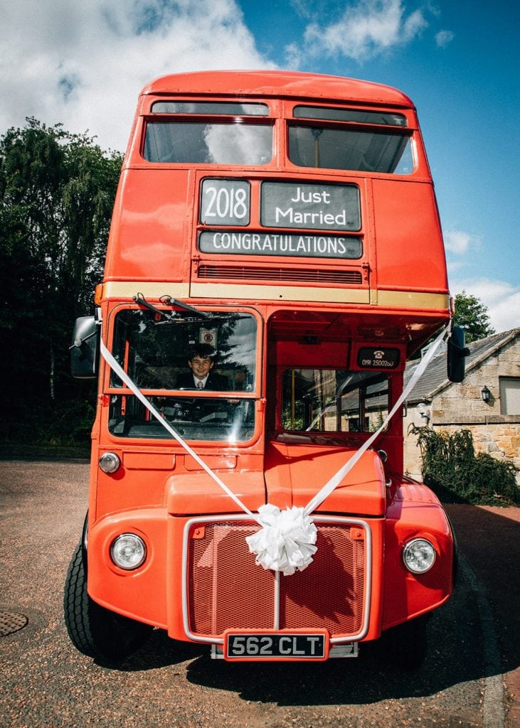 Grooms son driving a red london bus at Linden Hall in Northumberland
