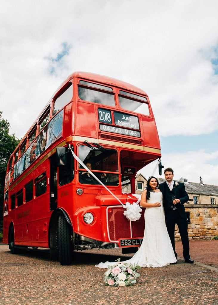 Bride & Groom in from of a red london bus at Linden Hall in Northumberland
