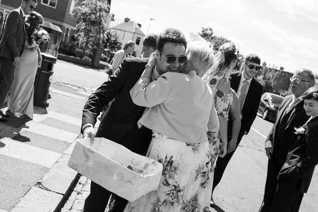 Grooms mum hugging him outside St. Cuthberts Church in Blyth, Northumberland
