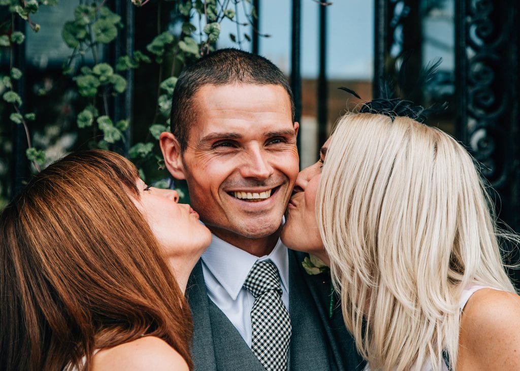 Groom having a kiss from his sisters outside of Morpeth Town Hall in Northumberland