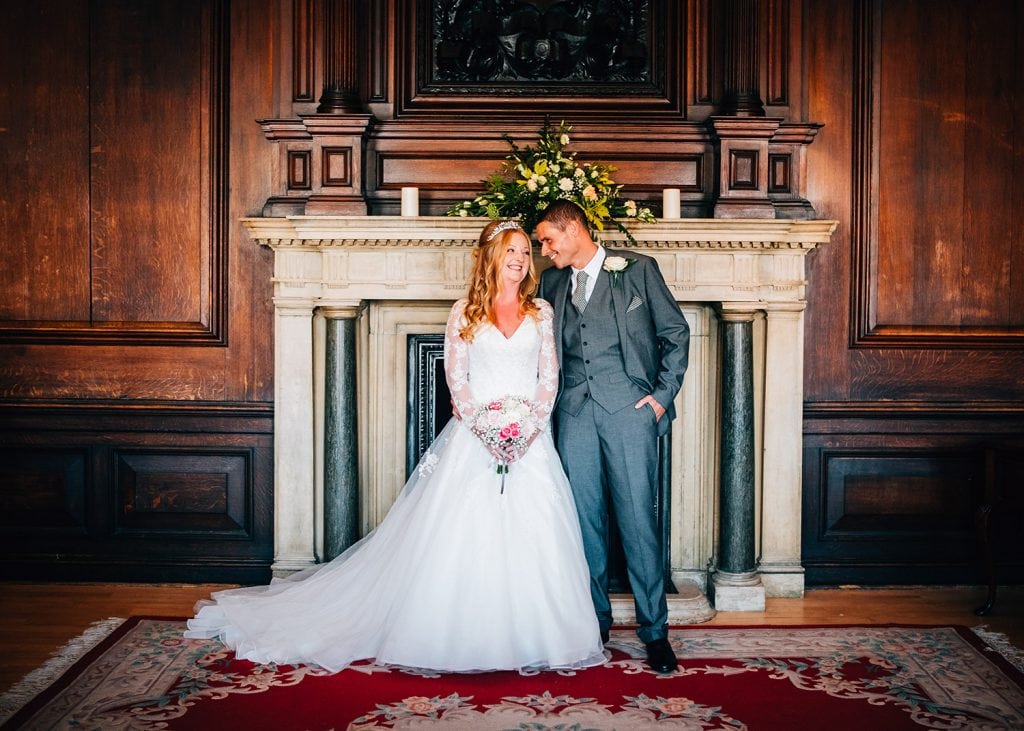 The bride & groom smiling at each other in front of the Ballroom fireplace in Morpeth Registry Office. Northumberland