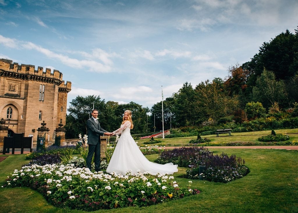 The bride & groom holding hands at Carlisle Park in Morpeth, Northumberland