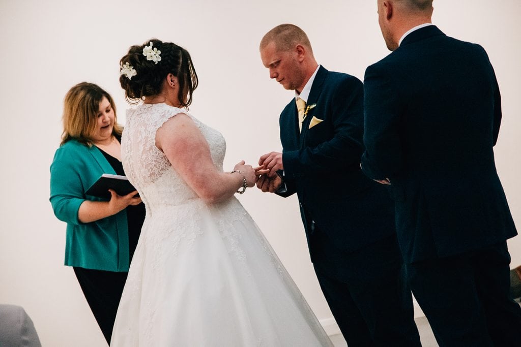 groom putting a wedding ring on the bride finger