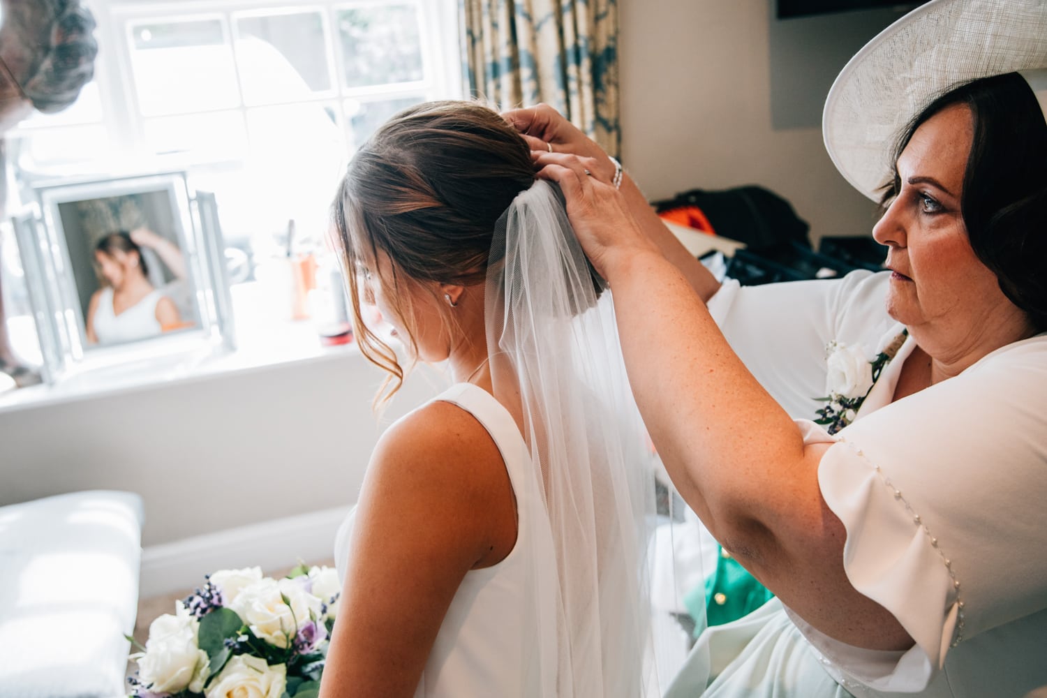 Brides mother fitting her veil